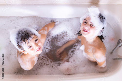Fotografie, Obraz Two kids taking a bath looking a camera