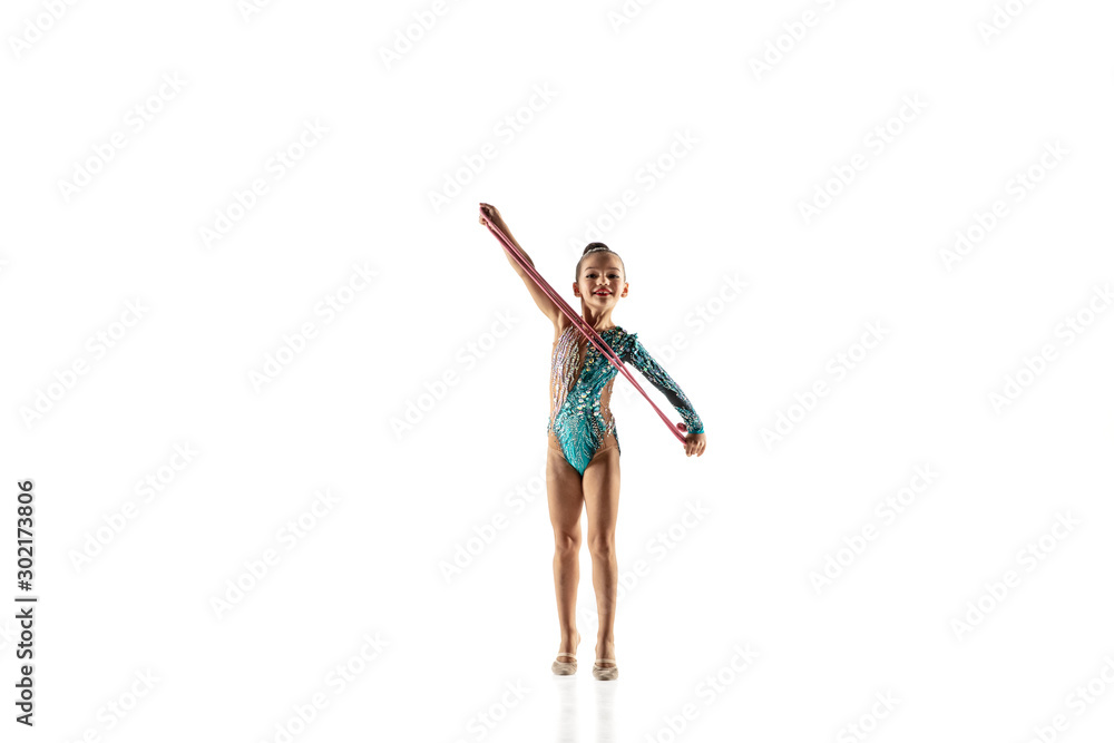 Little flexible girl isolated on white studio background. Little female model as a rhythmic gymnastics artist in bright leotard. Grace in motion, action and sport. Doing exercises with the jump rope.