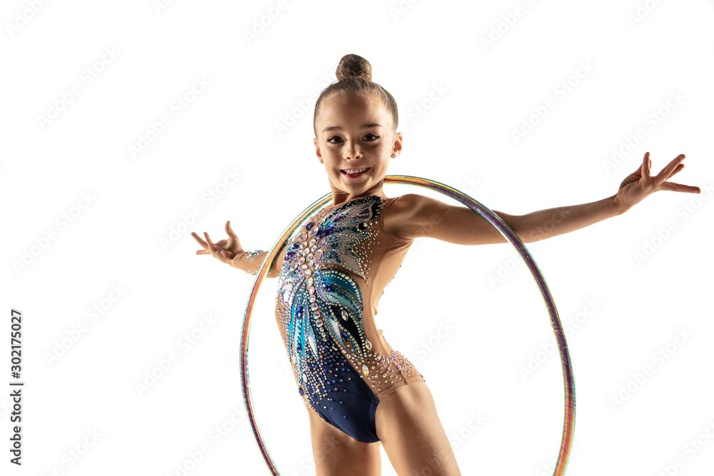 Little flexible girl isolated on white studio background. Little female  model as a rhythmic gymnastics artist in bright leotard. Grace in motion,  action and sport. Doing exercises with the hoop. Stock Photo