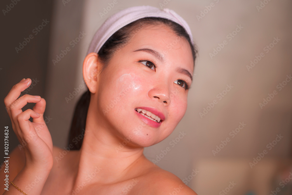 domestic lifestyle portrait of young beautiful and happy Asian Korean woman applying facial cosmetic cream smiling cheerful to bathroom mirror in beauty skin care domestic lifestyle portrait of young beautiful and happy Asian Korean woman applying facial cosmetic cream smiling cheerful to bathroom mirror in beauty skin care