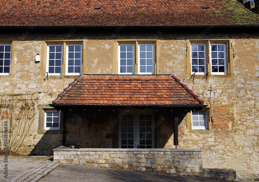 Gepflegtes altes Haus mit Ziegel-Vordach und hellbrauner Steinfassade