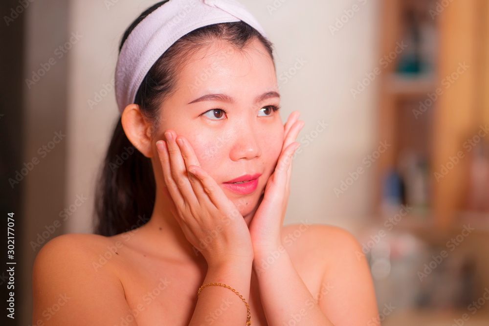 domestic lifestyle portrait of young beautiful and happy Asian Korean woman applying facial cosmetic cream smiling playful to bathroom mirror in beauty skin care domestic lifestyle portrait of young beautiful and happy Asian Korean woman applying facial cosmetic cream smiling playful to bathroom mirror in beauty skin care