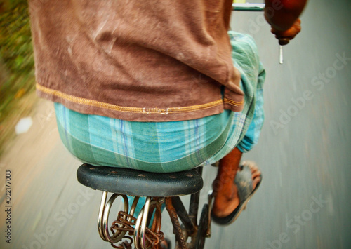 close up of saddle and back of a south indian man on an old bike