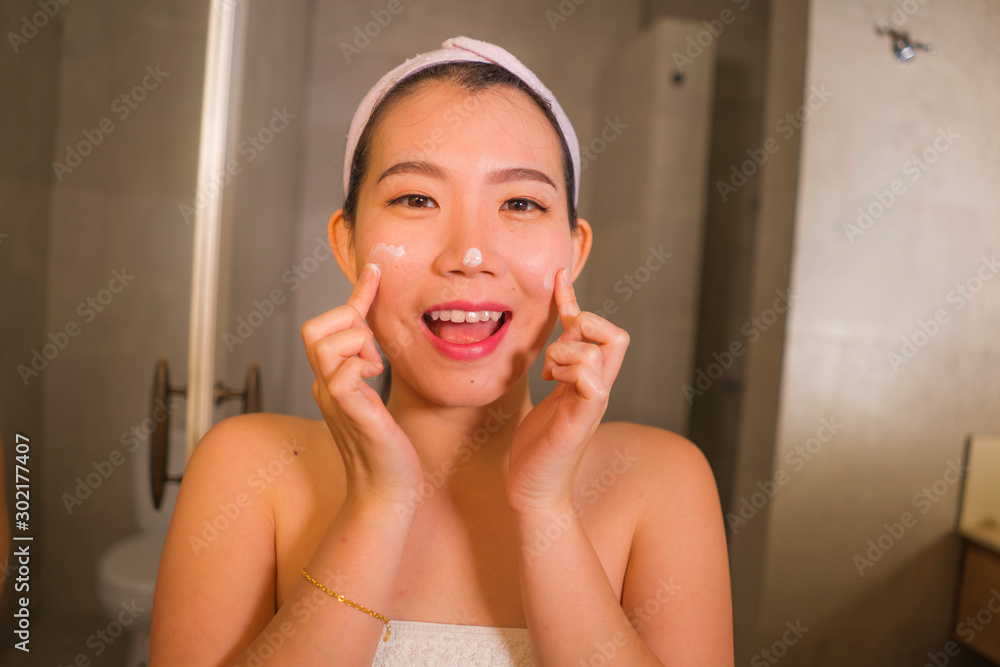 domestic lifestyle portrait of young beautiful and happy Asian Korean woman applying facial cosmetic cream smiling cheerful to bathroom mirror in beauty skin care domestic lifestyle portrait of young beautiful and happy Asian Korean woman applying facial cosmetic cream smiling cheerful to bathroom mirror in beauty skin care