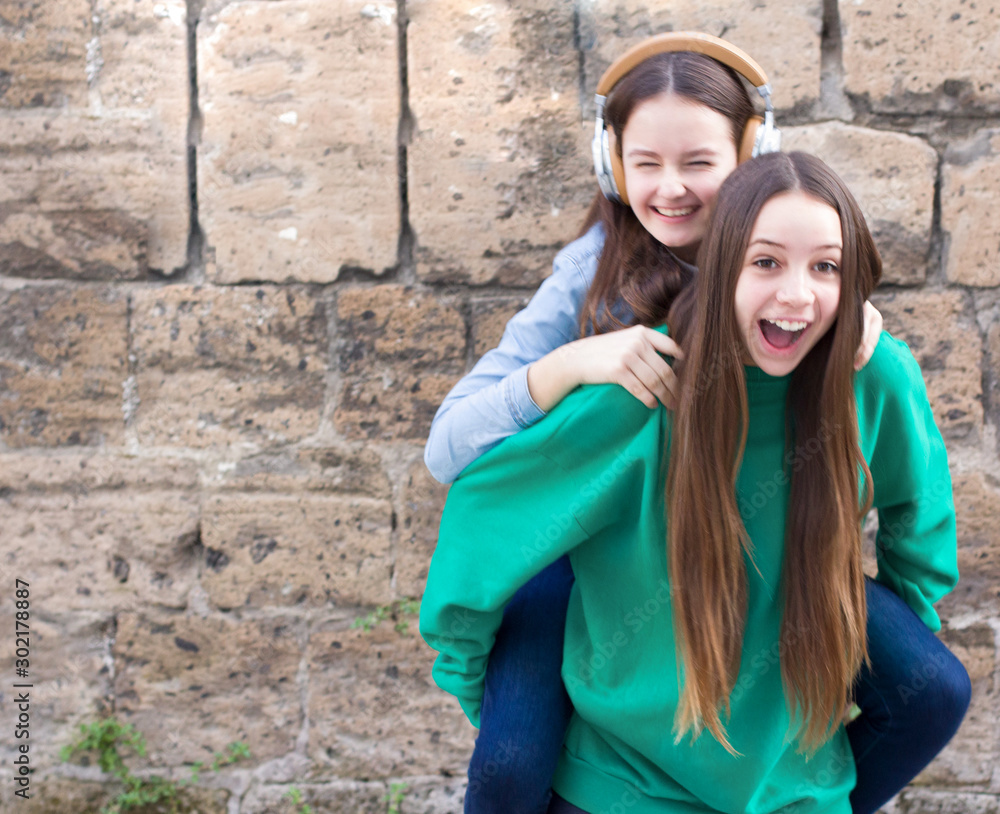 Teen girls have fun at old brick wall background Teen girls have fun at old brick wall background