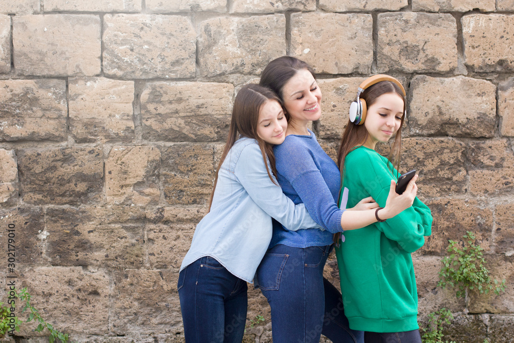 Teen girls and mother have fun at old brick wall background