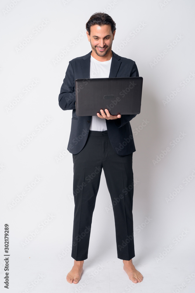 Full body shot of happy Hispanic businessman using laptop Full body shot of happy Hispanic businessman using laptop