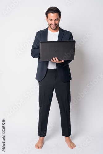 Full body shot of happy Hispanic businessman using laptop