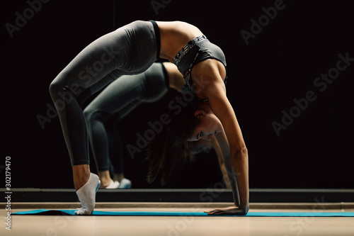 Sportswoman on stretch sitting on rug in sports hall