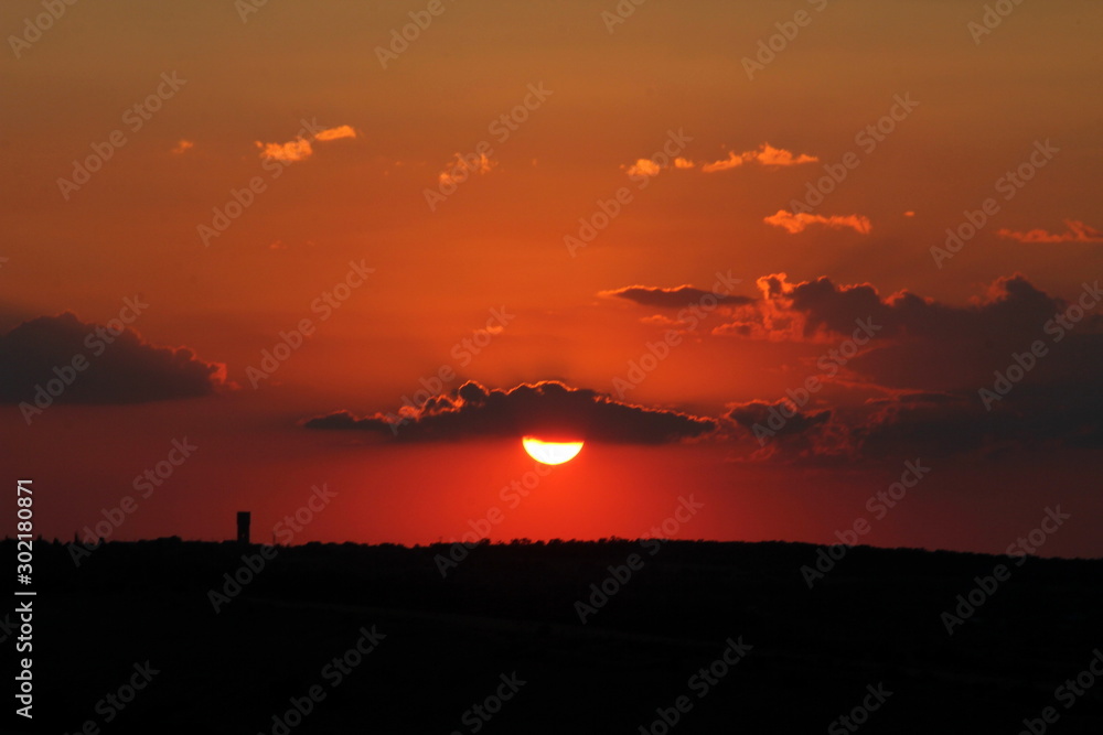 Red summer sun at sunset among the clouds. Red summer sun at sunset among the clouds.