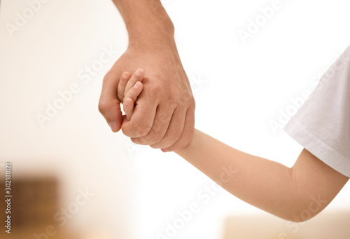 Father holding hands with his child indoors, closeup. Happy family © New Africa