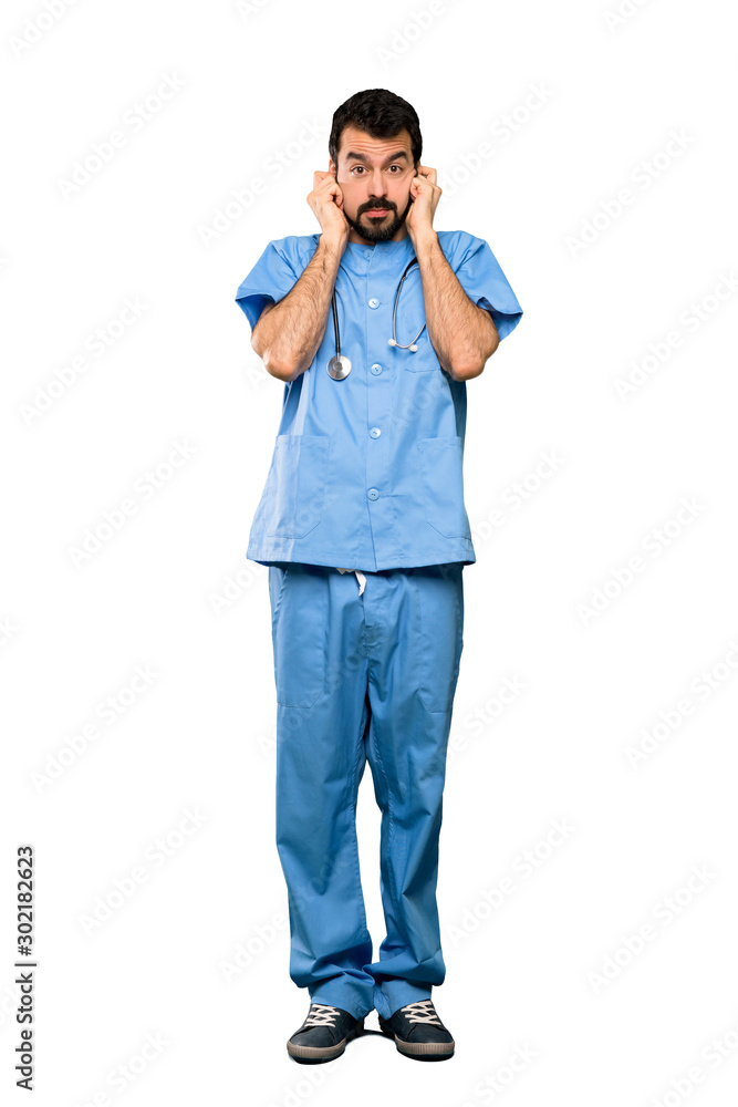 Full-length shot of Surgeon doctor man frustrated and covering ears over isolated white background Full-length shot of Surgeon doctor man frustrated and covering ears over isolated white background