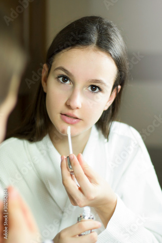 Female beauty  beautiful teen girl applying make up in bathroom at home.
