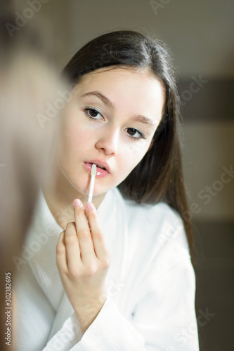 Female beauty, beautiful teen girl applying make up in bathroom at home.