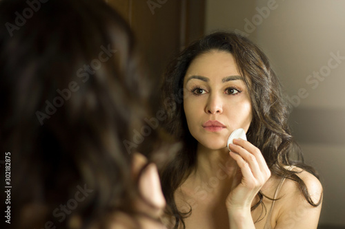 Female beauty  beautiful young woman applying cream on face in bathroom at home.