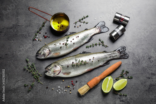 Flat lay composition with raw cutthroat trout fish on grey table