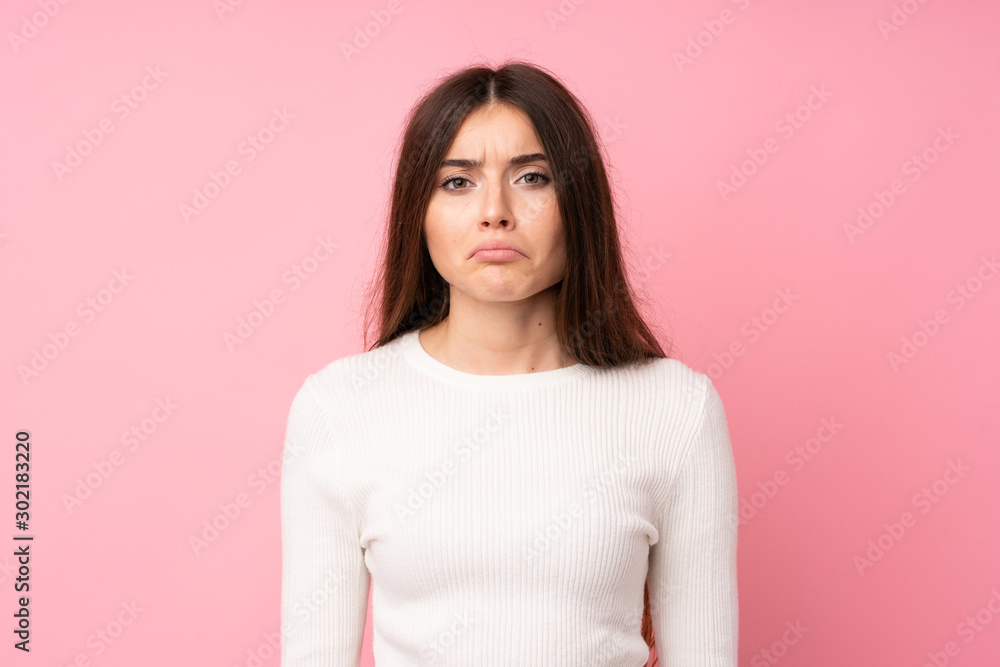 Fototapeta premium Young woman over isolated pink background sad