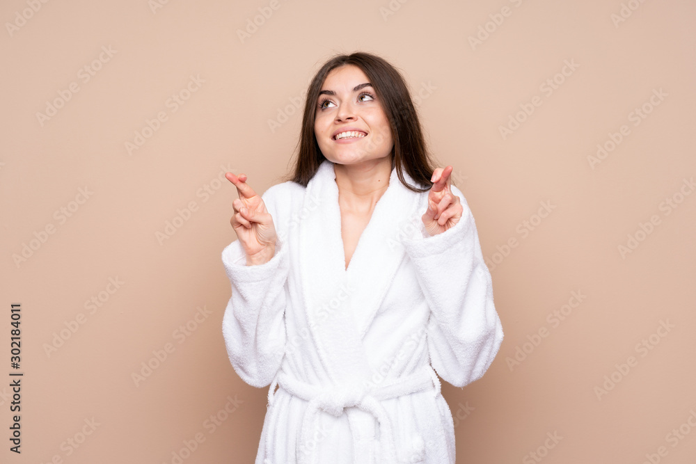 Young girl in a bathrobe over isolated background with fingers crossing Young girl in a bathrobe over isolated background with fingers crossing