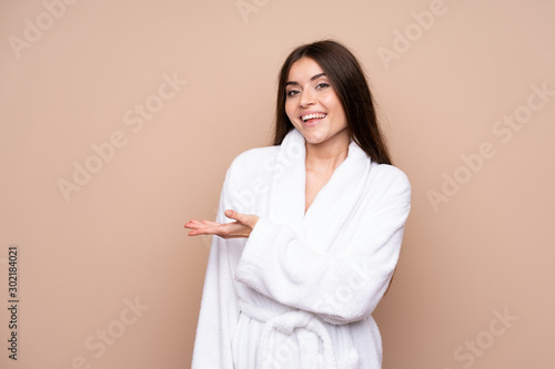 Young girl in a bathrobe over isolated background extending hands to the side for inviting to come