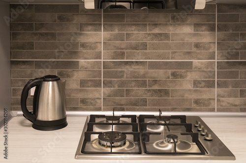 Interior of a modern kitchen. Close-up of electric kettle and gas hob on grey tile backsplash photo