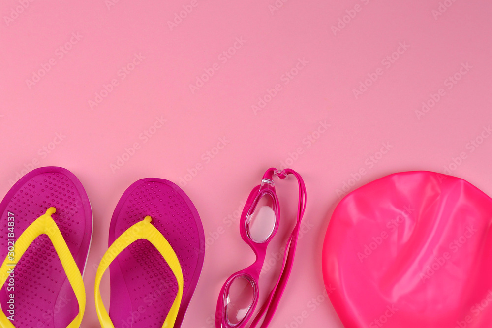 Flat lay composition with swimming accessories on pink background. Space for text