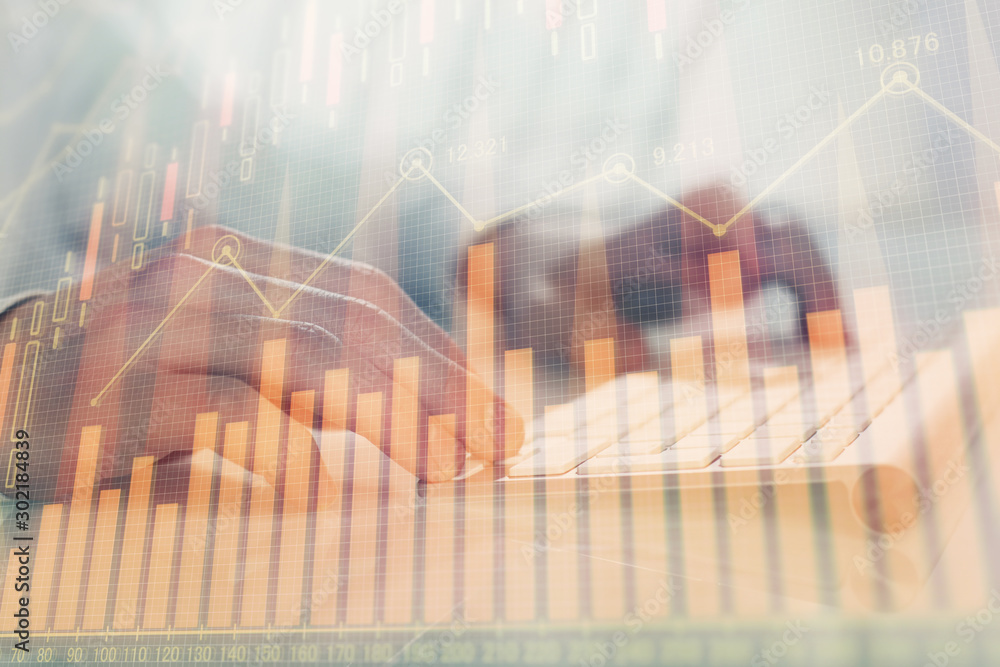 Double exposure of graph with man typing on computer in office on background. Concept of hard work.