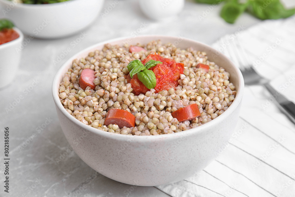Tasty buckwheat porridge with sausages on grey marble table Tasty buckwheat porridge with sausages on grey marble table