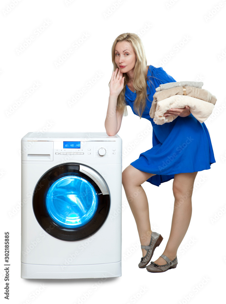 beautiful woman in a blue dress next to a new washing machine holds a stack of clean laundry.. beautiful woman in a blue dress next to a new washing machine holds a stack of clean laundry..