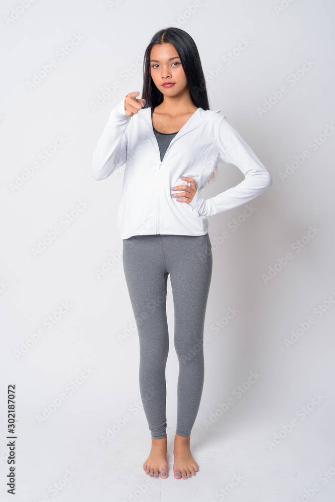 Full body shot of young Asian woman pointing at camera ready for gym Full body shot of young Asian woman pointing at camera ready for gym