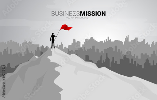 silhouette of businessman with the red flag standing on the top of mountain and city background. Concept of Goal, Mission, Vision, Success in Career path.