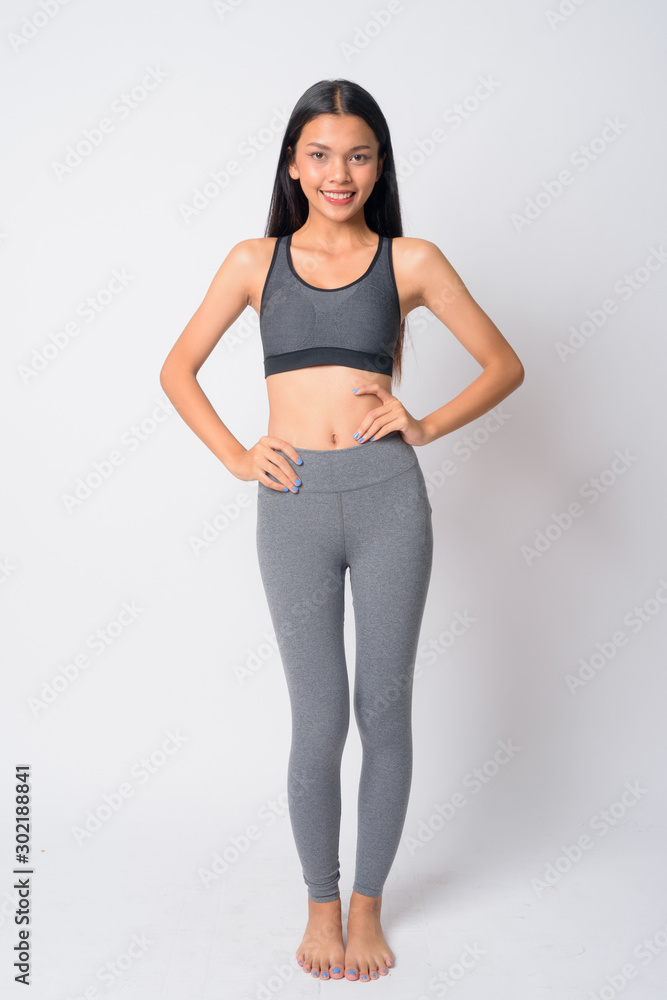 Full body shot of happy young Asian woman smiling ready for gym Full body shot of happy young Asian woman smiling ready for gym