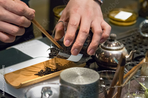 Male hand dosing tea in strands to make black tea.