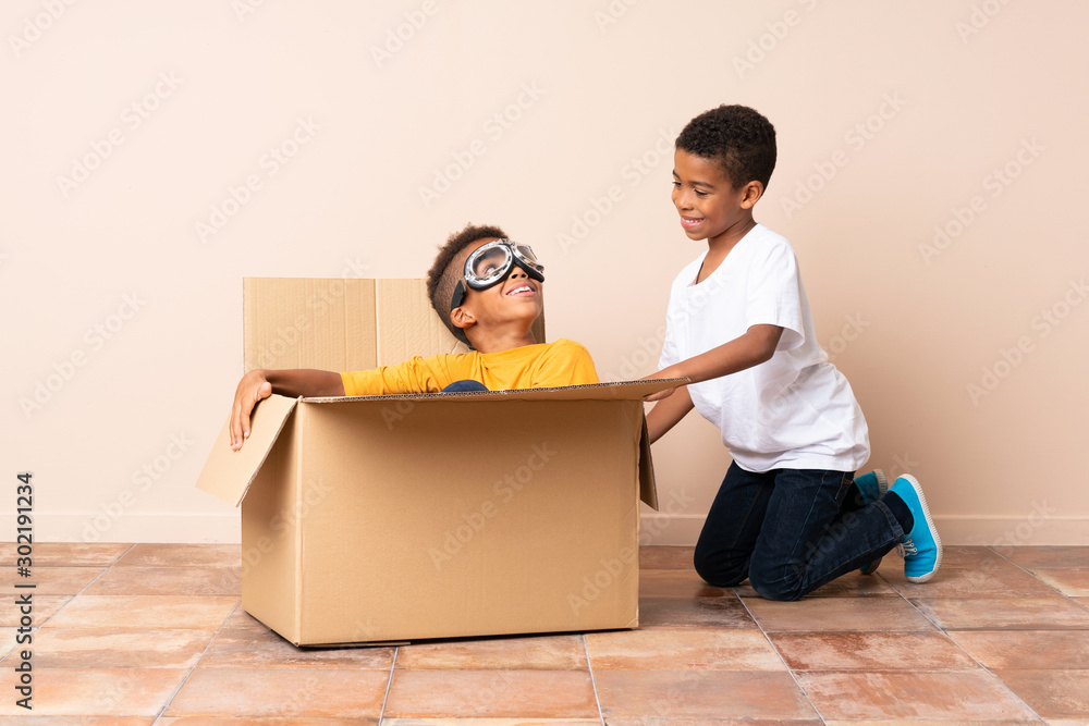 African American brothers playing. Boy inside a cardboard box with aviator glasses African American brothers playing. Boy inside a cardboard box with aviator glasses