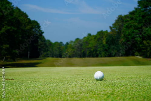 White golf ball near hole on green grass.