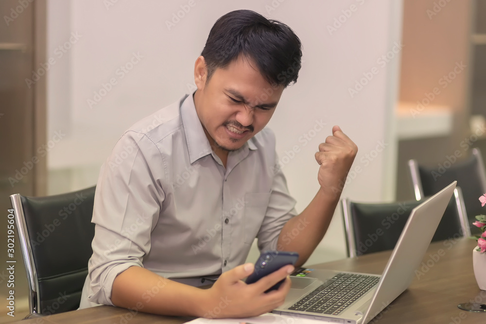 Asian businessmen are happy to work successfully with laptop and paper on the wooden table in the office building. Asian businessmen are happy to work successfully with laptop and paper on the wooden table in the office building.