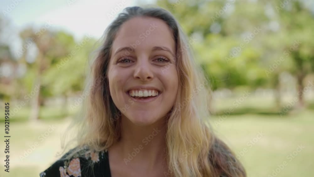 Portrait of a blonde young woman looking to camera feeling joyful and happy at outdoors - smiling into the camera Portrait of a blonde young woman looking to camera feeling joyful and happy at outdoors - smiling into the camera