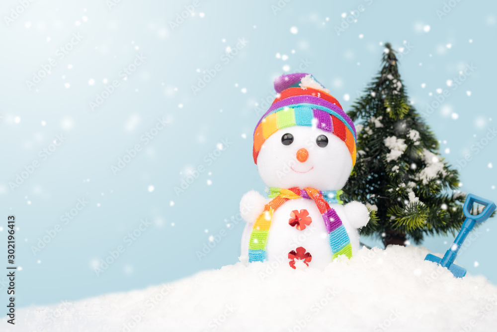 Cute snowman on fake snow with copy space on blue background.