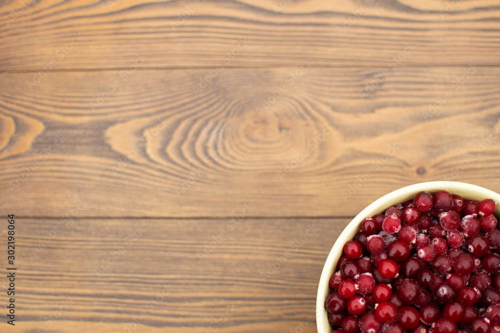 Top view rustic wooden background, bowl full of fresh cranberry in the corner, copy space Top view rustic wooden background, bowl full of fresh cranberry in the corner, copy space