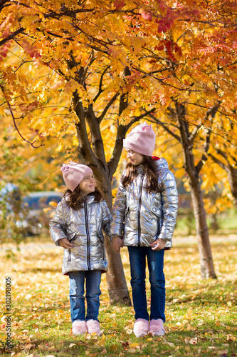 little girls in identical clothes have fun walking in the autumn Park