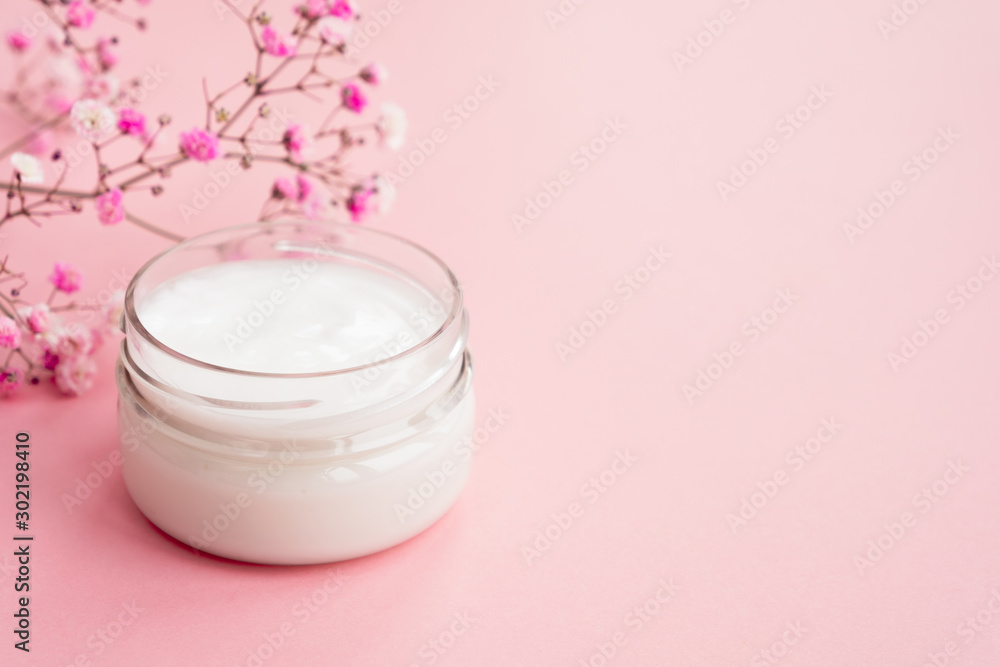 Cosmetic cream in a jar and flowers on a light pink background. Concept natural cosmetics, beauty, skincare. Close up, copy space Cosmetic cream in a jar and flowers on a light pink background. Concept natural cosmetics, beauty, skincare. Close up, copy space