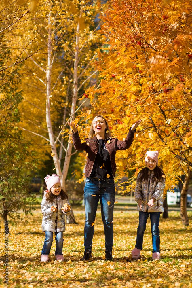 little girls in identical clothes with their mother have fun walking in the autumn Park