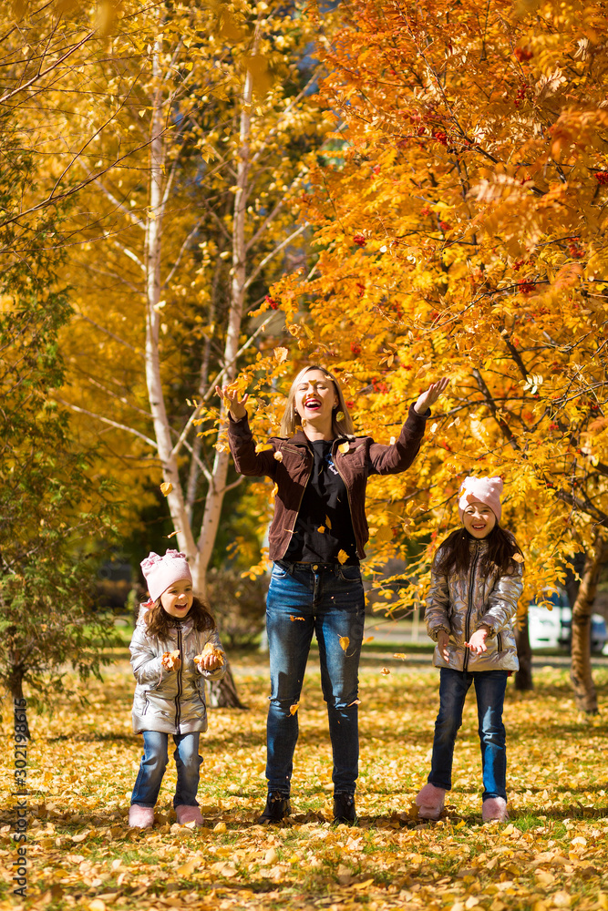 little girls in identical clothes with their mother have fun walking in the autumn Park little girls in identical clothes with their mother have fun walking in the autumn Park