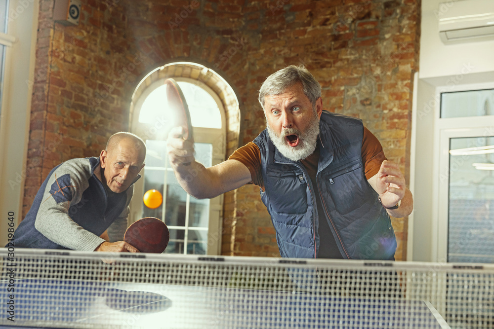 Senior men playing table tennis in workplace, having fun. Friends in casual  clothes play ping pong together at sunny day. Concept of leisure activity,  sport, friendship, teambuilding, teamwork. Stock Photo | Adobe