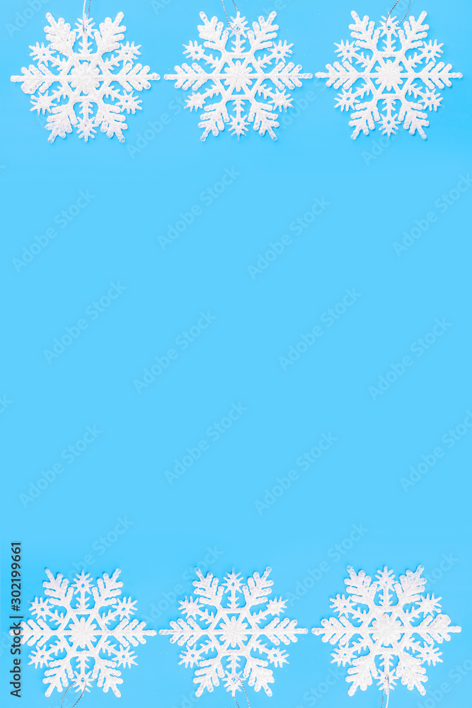 Christmas border of white snowflakes isolated on a blue background. Concept banner border frame background for Christmas and New Year. Copy space