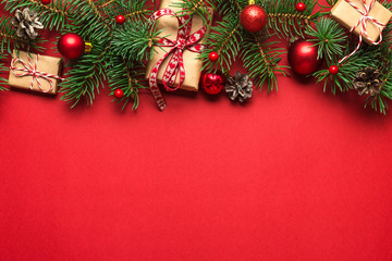 Christmas composition made of fir branches, gift boxes, red holiday decorations on red background