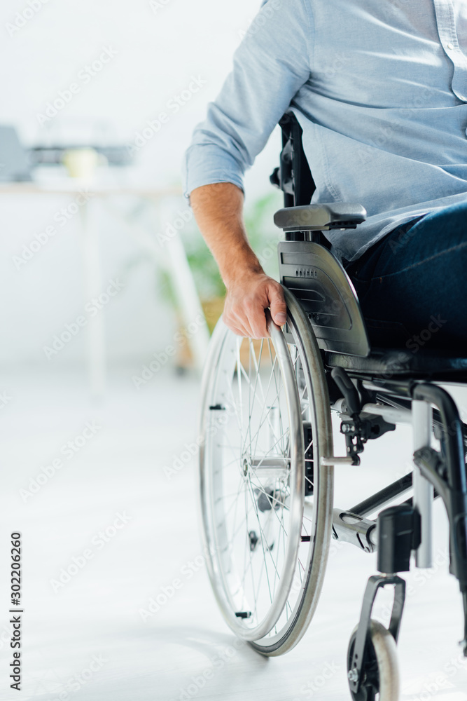 partial view of man sitting in wheelchair in living room partial view of man sitting in wheelchair in living room