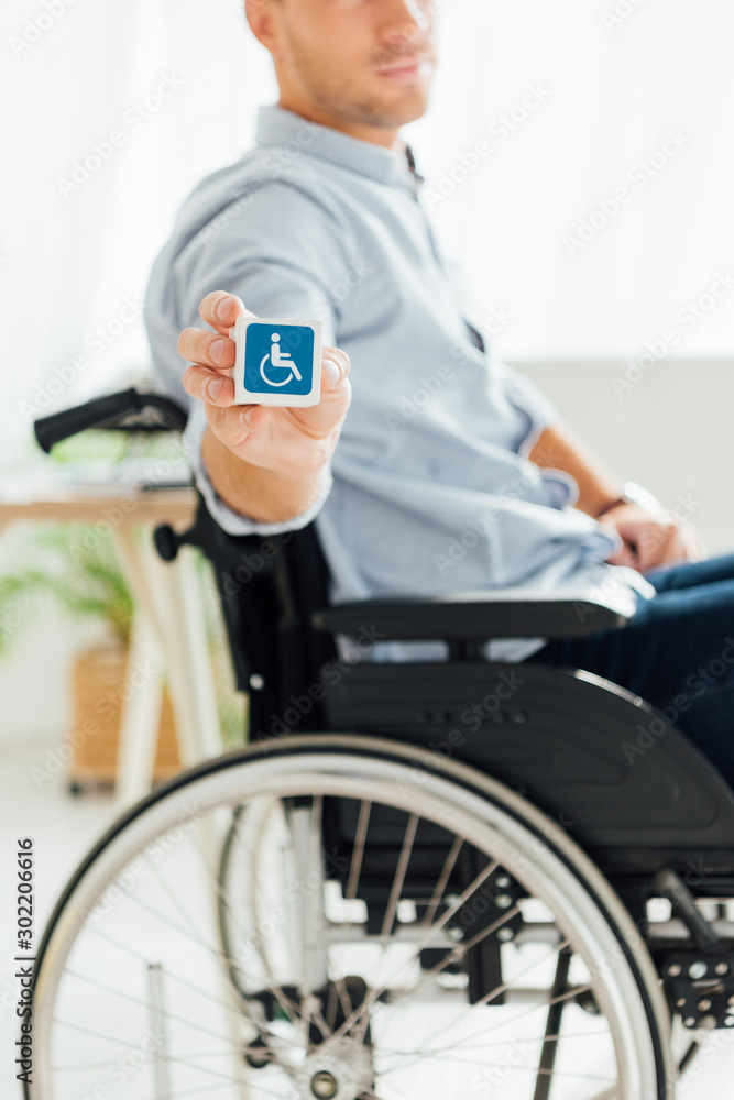 Cropped view of man in wheelchair showing cube with disabled sign