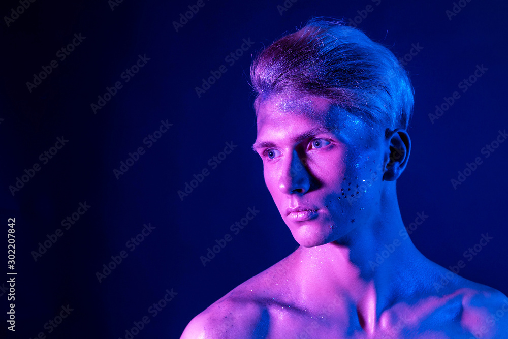 Handsome pumped up guy with naked torsos. Sports guy, attractive male body. Studio shooting with color filters Handsome pumped up guy with naked torsos. Sports guy, attractive male body. Studio shooting with color filters
