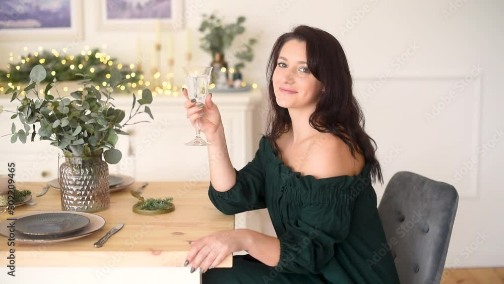 Attractive girl with long brunette hair sitting wize wine glass at christmas served table Attractive girl with long brunette hair sitting wize wine glass at christmas served table