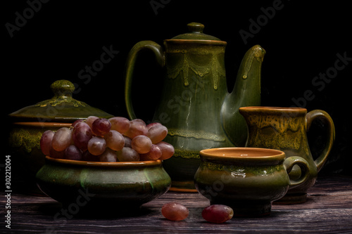 A bunch of grapes in an old clay cup, on a dark background